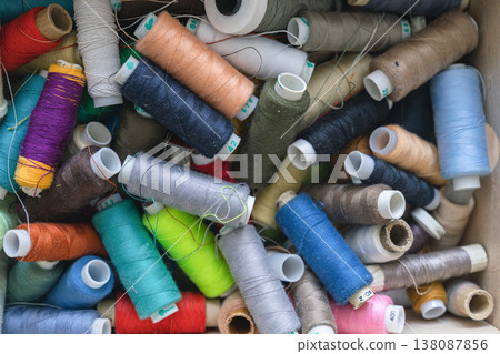 Various spools of multicolored sewing thread filling a box, creating a textile background for craft and fashion concepts Various spools of multicolored sewing thread filling a box, creating a textile background for craft and fashion concepts 138087856