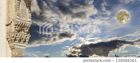 Arches in Islamic (Moorish) style (against the background of a beautiful evening sky with clouds with the super moon) in Alhambra, Granada, Spain 138088161
