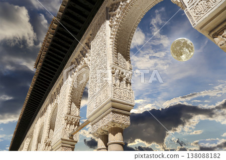 Arches in Islamic (Moorish) style (against the background of a beautiful evening sky with clouds with the super moon) in Alhambra, Granada, Spain Arches in Islamic (Moorish) style (against the background of a beautiful evening sky with clouds with the super moon) in Alhambra, Granada, Spain 138088182