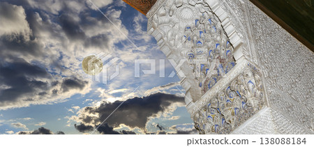 Arches in Islamic (Moorish) style (against the background of a beautiful evening sky with clouds with the super moon) in Alhambra, Granada, Spain 138088184