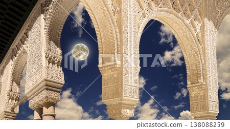 Arches in Islamic (Moorish) style (against the background of a beautiful evening sky with clouds with the super moon) in Alhambra, Granada, Spain 138088259