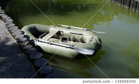 A dark green two-seater inflatable boat with oars for fishing and water recreation A dark green two-seater inflatable boat with oars for fishing and water recreation 138088308