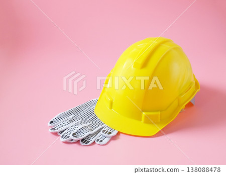 white knitted work gloves and safety helmet on color background. white knitted work gloves and safety helmet on color background. 138088478