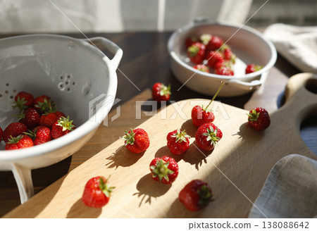 Fresh red strawberries on wooden cutting board in bright morning sunlight. Aesthetic food photography captures organic summer berries and rustic kitchenware for cottagecore slow living vibes. Fresh red strawberries on wooden cutting board in bright morning sunlight. Aesthetic food photography captures organic summer berries and rustic kitchenware for cottagecore slow living vibes. 138088642
