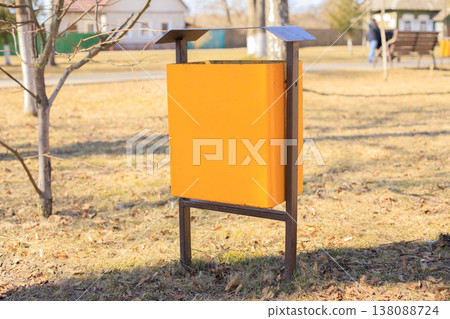 Yellow metal trash can in a public city park. Modern municipal waste container 138088724