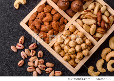 Wooden box with macadamia nuts, almonds, pistachios, and hazelnuts. Nuts as a food background Wooden box with macadamia nuts, almonds, pistachios, and hazelnuts. Nuts as a food background 138088820