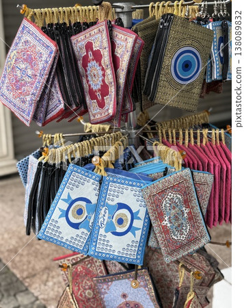 Colorful souvenir pouches featuring intricate patterns and evil eye designs displayed on a stand Colorful souvenir pouches featuring intricate patterns and evil eye designs displayed on a stand 138089832