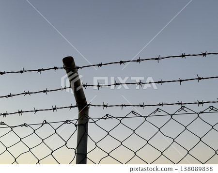 Barbed wire fence under a clear sky with copy space, suitable for background use Barbed wire fence under a clear sky with copy space, suitable for background use 138089838