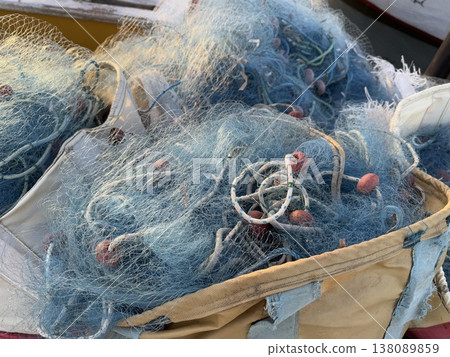 Fishing nets piled on a boat with visible ropes and weights, ideal for maritime theme background Fishing nets piled on a boat with visible ropes and weights, ideal for maritime theme background 138089859