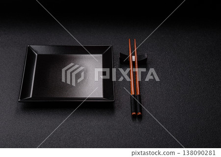 An empty ceramic square black plate with chopsticks for Asian food. An empty square plate An empty ceramic square black plate with chopsticks for Asian food. An empty square plate 138090281