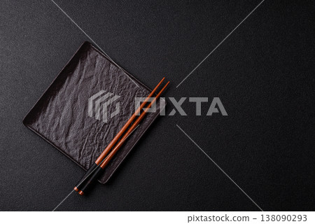 An empty ceramic square black plate with chopsticks for Asian food. An empty square plate An empty ceramic square black plate with chopsticks for Asian food. An empty square plate 138090293