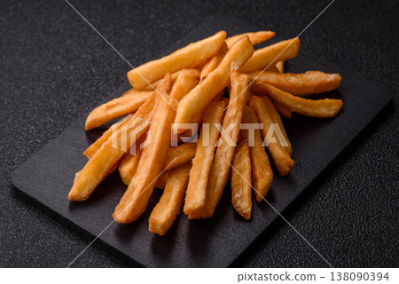 French fries, a salty, crispy, homemade snack with spices. French fries on a black background 138090394