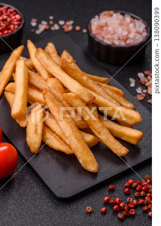 French fries, a salty, crispy, homemade snack with spices. French fries on a black background French fries, a salty, crispy, homemade snack with spices. French fries on a black background 138090399
