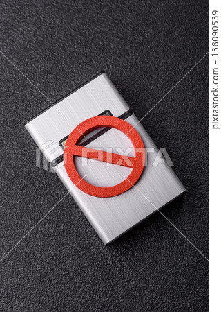 A metal cigarette box with a no smoking sign depicts a harmful habit. A cigarette box A metal cigarette box with a no smoking sign depicts a harmful habit. A cigarette box 138090539