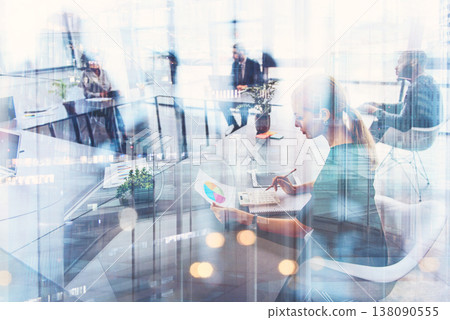 People working in a modern office space during the day while engaging in tasks and discussions 138090555