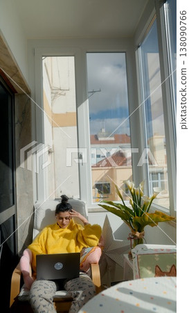 Evening Leisure With Gentle Ambiance. Woman In Cozy Yellow Hoodie Relaxes Near City Window At Twilight Evening Leisure With Gentle Ambiance. Woman In Cozy Yellow Hoodie Relaxes Near City Window At Twilight 138090766