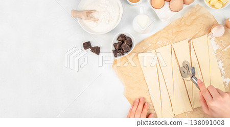 Puff pastry dough cut into triangles with baking ingredients on white background, top view process with copy space Puff pastry dough cut into triangles with baking ingredients on white background, top view process with copy space 138091008