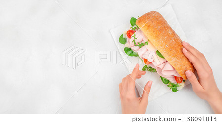 Sandwich with ham, cheese, arugula and tomato in hands on white background, top view food composition with copy space Sandwich with ham, cheese, arugula and tomato in hands on white background, top view food composition with copy space 138091013