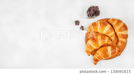 Croissants with chocolate pieces on wooden board over white background, top view bakery composition with copy space Croissants with chocolate pieces on wooden board over white background, top view bakery composition with copy space 138091015