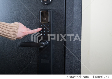 A woman opens a modern smart door lock with a digital keypad using a code. 138091237