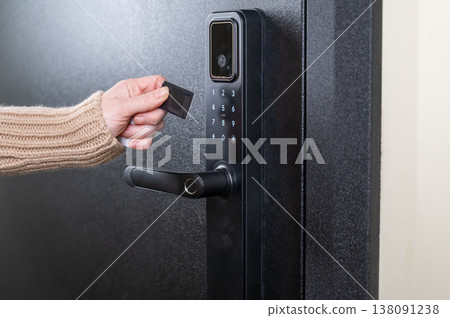 A woman opens a modern smart door lock using a contactless key. A woman opens a modern smart door lock using a contactless key. 138091238