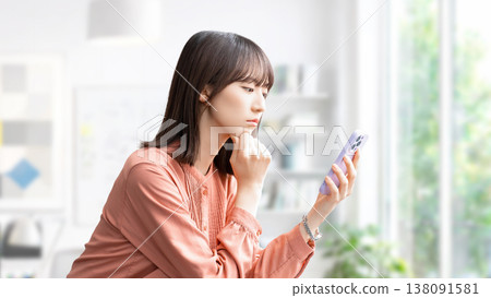 一位女性/女商人一邊看著她的智慧型手機一邊思考。 138091581