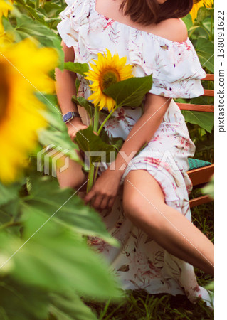 Woman sitting among sunflowers holding a flower in a tranquil outdoor setting. The warm scene reflects self care, women s wellness and emotional harmony during life transitions. Woman sitting among sunflowers holding a flower in a tranquil outdoor setting. The warm scene reflects self care, women s wellness and emotional harmony during life transitions. 138091622