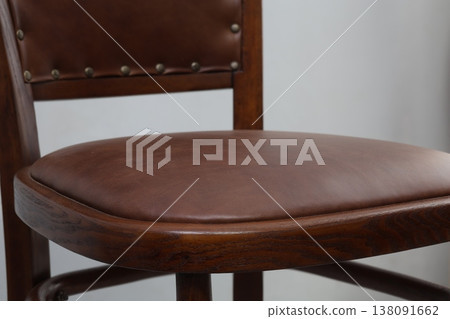 Elegant wooden chair with rich brown leather seat in a cozy indoor setting brings warmth and style to any room decor Elegant wooden chair with rich brown leather seat in a cozy indoor setting brings warmth and style to any room decor 138091662