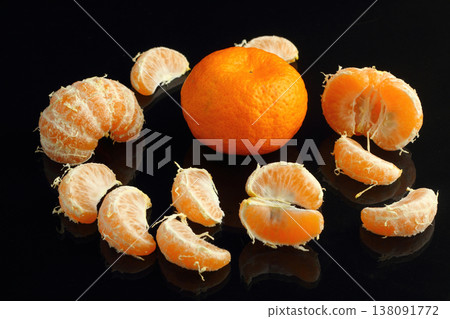 Peeled fresh tangerines with leaves on a black stone surface. Near mandarin slices. Seasonal citrus fruits, natural healthy foods. Close-up. Black stone background. Copyspace for text. 138091772
