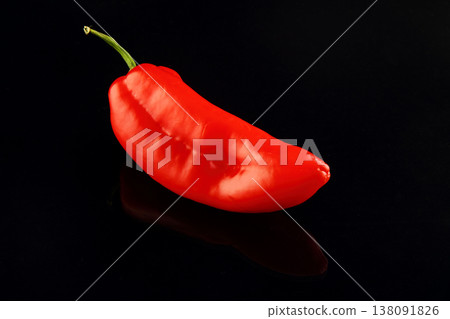One red hot chili pepper isolated on black. On a black glossy background with real reflection. One red hot chili pepper isolated on black. On a black glossy background with real reflection. 138091826