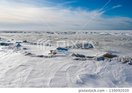 Frozen Baltic Sea Coast with Snow Drifts and Ice Under Blue Winter Sky Frozen Baltic Sea Coast with Snow Drifts and Ice Under Blue Winter Sky 138092030