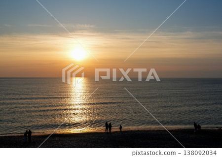 Beautiful Baltic Sea Sunset with Silhouettes of People Walking Along Sandy Beach at Golden Hour 138092034