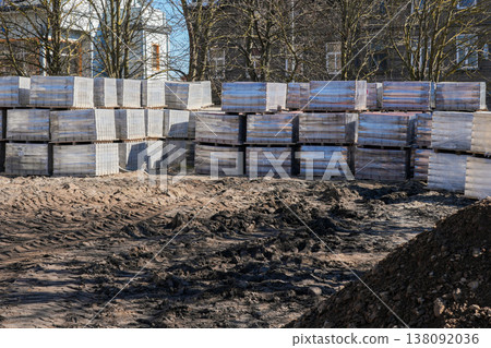 Stacked pallets of paving stones at urban construction site before reconstruction with muddy ground Stacked pallets of paving stones at urban construction site before reconstruction with muddy ground 138092036