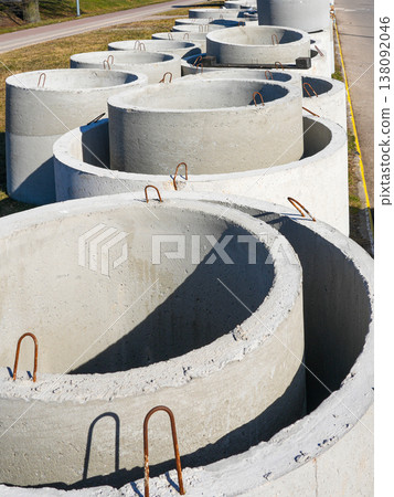 Concrete drainage rings stacked outdoors with metal handles on construction materials storage site Concrete drainage rings stacked outdoors with metal handles on construction materials storage site 138092046