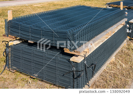 Stacked welded wire mesh fence panels on pallets at outdoor construction materials storage site 138092049