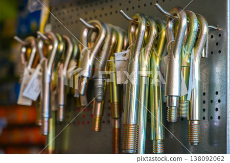 Metal towing eye bolts hooks hanging on pegboard in hardware store industrial steel tools display Metal towing eye bolts hooks hanging on pegboard in hardware store industrial steel tools display 138092062