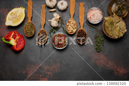 Spices on a dark background in wooden spoons: pepper, cloves, ginger, allspice and bay leaf, salt, thyme. Spices on a dark background in wooden spoons: pepper, cloves, ginger, allspice and bay leaf, salt, thyme. 138092320