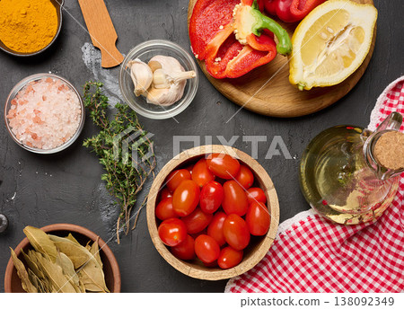 Fresh vegetables and spices with cherry tomatoes, garlic, lemon, bell pepper, aromatic herbs, olive oil and salt on a dark textured surface Fresh vegetables and spices with cherry tomatoes, garlic, lemon, bell pepper, aromatic herbs, olive oil and salt on a dark textured surface 138092349