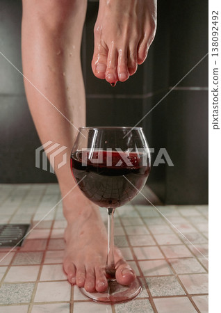 Foot fetish. A woman dips her toes in a glass of red wine. Foot fetish. A woman dips her toes in a glass of red wine. 138092492