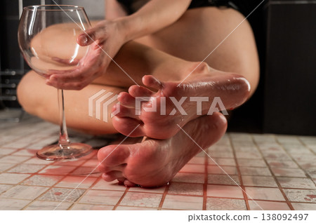 Foot fetish. A woman pours wine from a glass onto her feet in the shower. Foot fetish. A woman pours wine from a glass onto her feet in the shower. 138092497