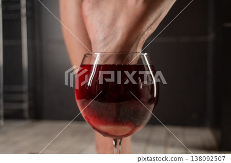 Foot fetish. A woman dips her toes in a glass of red wine. Foot fetish. A woman dips her toes in a glass of red wine. 138092507
