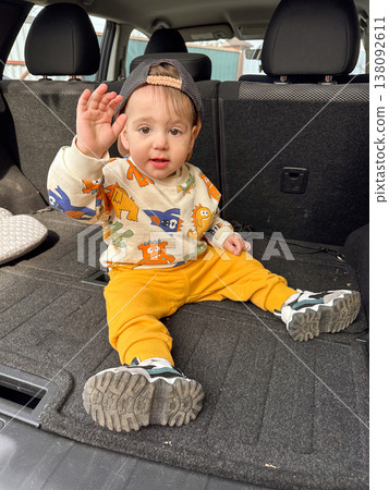 Toddler sitting in open car trunk during family road trip 138092611