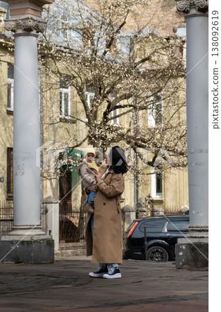 Mother holding toddler on city street in spring Mother holding toddler on city street in spring 138092619