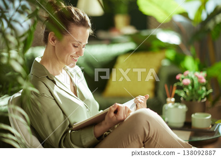 Relaxed Woman Reading Book in Bright Green Living Room Relaxed Woman Reading Book in Bright Green Living Room 138092887