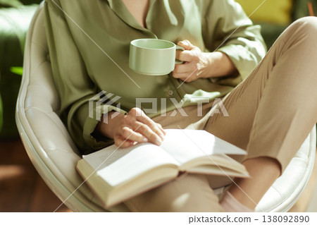 Woman Reading with Tea in Sunlit Modern Home 138092890