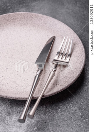 An empty round ceramic plate, knife, and fork as a dining table setting. An empty plate An empty round ceramic plate, knife, and fork as a dining table setting. An empty plate 138092911