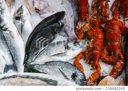 Fresh seafood assortment on ice at a traditional fish market. A variety of raw dorado, sea bream, and large fish fillets displayed with lobster for gourmet cooking Fresh seafood assortment on ice at a traditional fish market. A variety of raw dorado, sea bream, and large fish fillets displayed with lobster for gourmet cooking 138093243