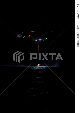 night vision firefighting helicopter takes water from the sea. 138094063