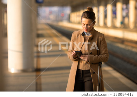Woman with Crutch Using Tablet on Train Platform 138094412