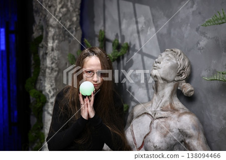 Woman gestures with bright green sphere near ancient stone statue Woman gestures with bright green sphere near ancient stone statue 138094466